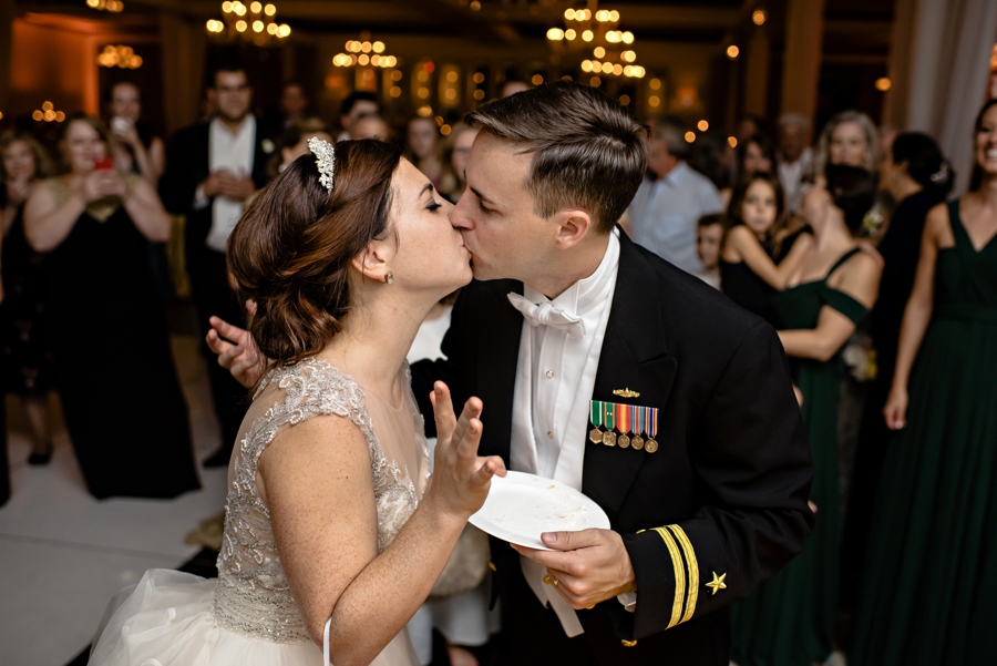 A couple kiss after feeding each other wedding cake at their Vie Wedding reception.